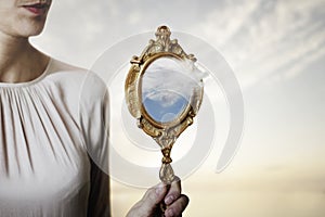 Surreal situation of a cloud coming out of a mirror held by a woman