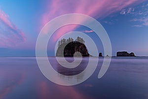 Surreal sunset of pink and purple clouds and island reflected in water