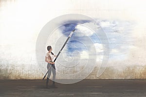 Surreal woman with giant brush draws a sky on a city wall