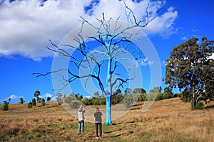 Surrealistic naked blue tree in park with surprised women