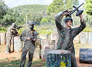 Surrendered paintball player in protective form and mask with paint splash standing with his hands up