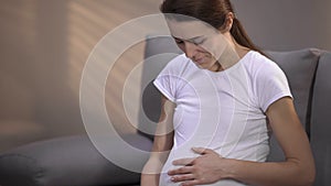 Surrogate mother smiling, feeling baby moving in belly, positive emotions