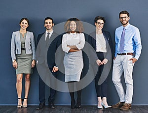 Surrounded by business minded individuals. Studio shot of a group of businesspeople standing in line against a gray