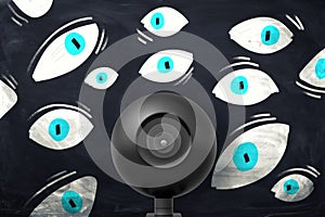 Surveillance camera among many drawn eyes on board photo