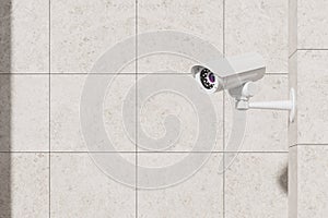 Surveillance camera mounted on empty tiled wall, safety control outdoors