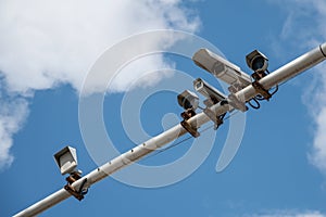 surveillance cameras and radars on a metal pole above the road