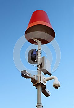 Surveillance system with an orange warning light located on a pole in the open. The threat of privacy and the protection of