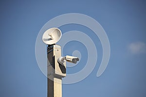 Surveillance system with an orange warning light located on a pole in the open. The threat of privacy and the protection of