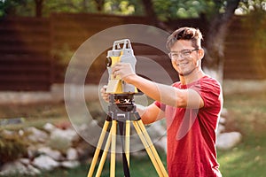 survey engineer in garden elevation using and working with theodolite