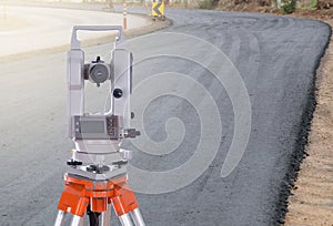 Survey equipment theodolite on a tripod. with road under constr