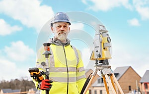 Surveyor builder site engineer with theodolite total station at construction site outdoors