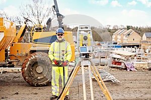 Surveyor builder site engineer with theodolite total station at construction site outdoors during surveying work