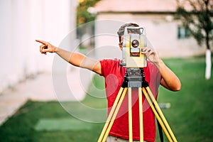 Surveyor cartographer engineer working with total station on garden elevation photo