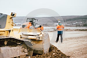 Surveyor engineer with GPS system outdoors at highway construction site, excavator and bulldozer details