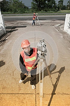 Surveyor or Engineer making measure with partner on the field.