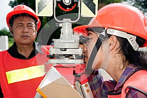 Surveyor or Engineer setting prism reflector with partner on the field.