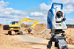 Surveyor equipment theodolie at construction site with excavator