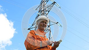 Surveyor in jumpsuit and helmet smiles holding smartphone