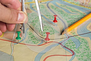 The surveyor marks the distance on the map with red buttons. Close-up of a surveyor hand with a compass