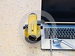 Surveyor`s telescope, Notebook Computers and wrench on floor. Construction industry concept.