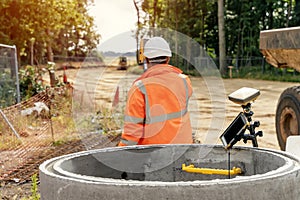 Surveyor site engineer with total positioning station on the construction site of the new road construction with construction