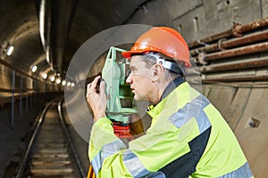 Surveyor with theodolite level at underground railway tunnel construction work