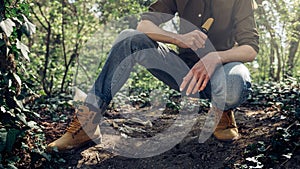 Survival Bushcraft Forest Concept. Unrecognizable woman sitting and holds neck knife in hands