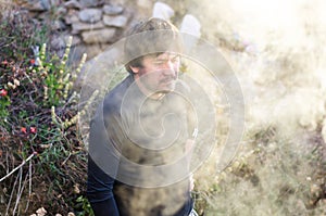 Survival man is making camp fire in the winter woods