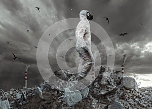 Survivor with white overall and gas mask reach the top of garbage dump and watching to the apocalyptic sky