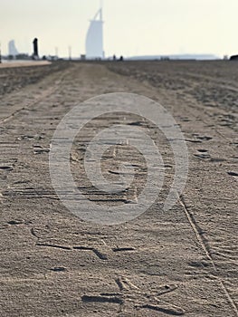 Suset view to ornamented sand road. Burj Al Arab building on background