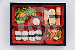 Sushi Bento Served with Japanese Rice Wraped with Seaweed and Shrimp, Kani and Tamagoyaki Sushi with Seaweed Salad.