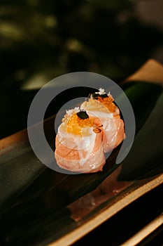 this is a sushi on a black plate and sits on a gold rim