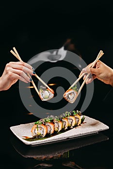 Sushi Chuka Roll and Chinese chopsticks in hands