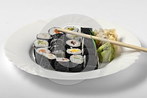 Sushi dish of traditional Japanese cuisine on a white plate, wooden sticks