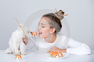 Sushi. Fashion portrait of beauty model girl eating sushi rolls, japanese food. Beautiful woman holding chopsticks with