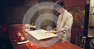 Sushi, food and chef at restaurant cooking on table at diner or cuisine ingredients at night. Kitchen, knife and