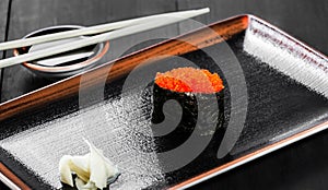 Sushi Gunkan maki with salmon caviar on dark wooden background. Japanese cuisine. Top view.