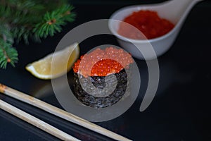 Sushi gunkan with rice and red caviar on a black background. Good New Year spirit.