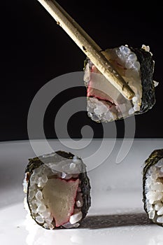 sushi kani on a white plate with one hand holding rashi, selective focus