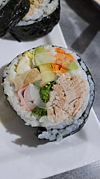 Sushi or kimbap full of tuna, carrot, crabstick, eggroll, cucumbar , mustard photo