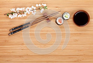 Sushi maki with fresh sakura branch over bamboo table