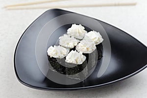 Sushi Maki on a plate. Triangular black plate with sushi on a light background.