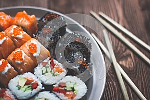 Sushi Maki Rolls with Chopsticks on a Wooden Platter with Wasabi - Viewed from Above Isolated on Grey Wood Background.