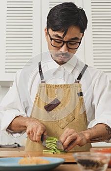 Sushi master chef slice fresh cucumber on chopping board in the kitchen. Knife in motion