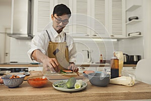 Sushi master preparing rolls on kitchen. Front view portrait of asian chef cooking at home