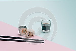 Sushi minimal concept. Chopsticks, one piece of rice rice cube with tuna, carrots and another with salomon cucumber roll in nori