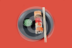 Sushi mix rolls in a black plate on red background