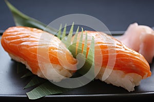 Sushi nigiri with rice and neta topping salmon fish on black background. photo