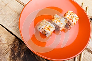 Sushi on an orange plate, on a wooden background.
