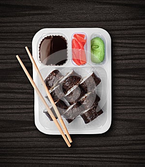 Sushi in plastic box closeup on black wooden background